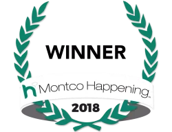 Logo of Montco Happening, featuring a circular design with laurel leaves in teal and a white ribbon displaying the text "Montco Happening" along with the year "2016." This emblem signifies community engagement and local events in Montgomery County, Pennsylvania.